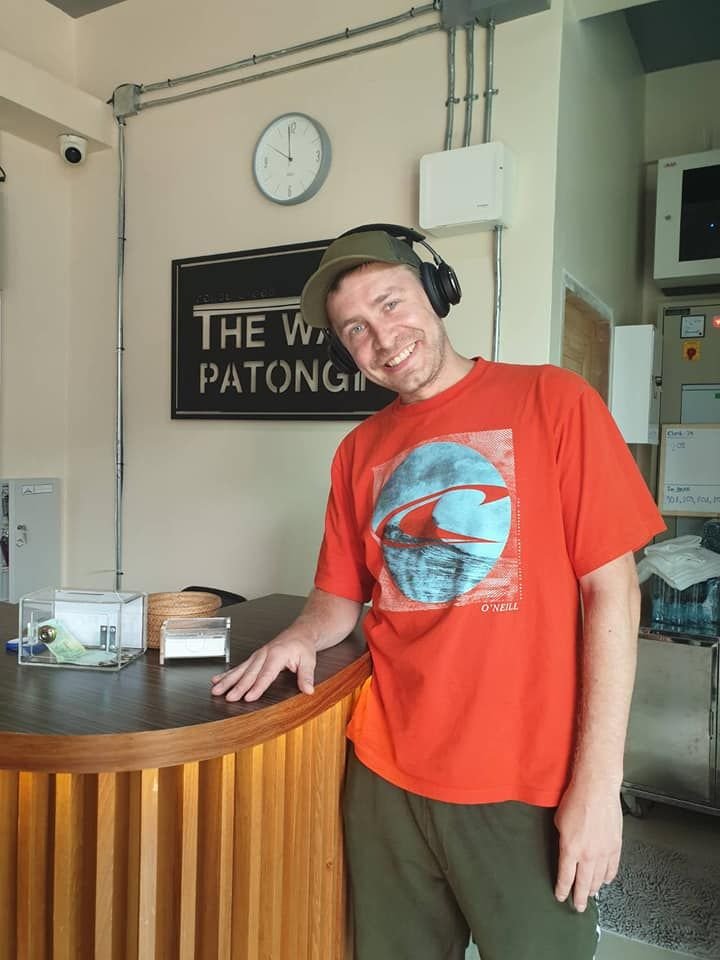 Smiling guest in an orange T-shirt at The Way Patong reception desk