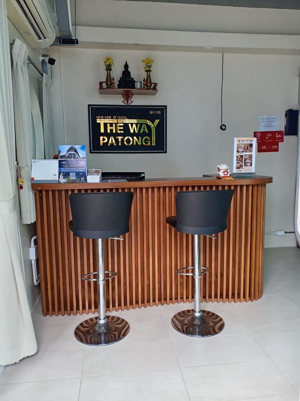 Wooden reception desk with The Way Patong logo, open 9:00–23:00