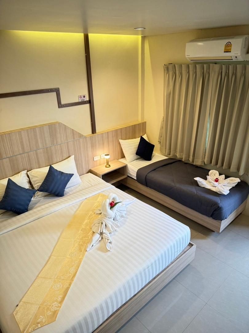 Air-conditioned room with king bed, sofa bed and window curtains at The Way Patong Hotel