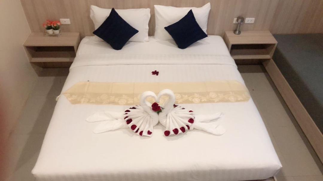 King bed decorated with towel swans and rose petals at The Way Patong Hotel